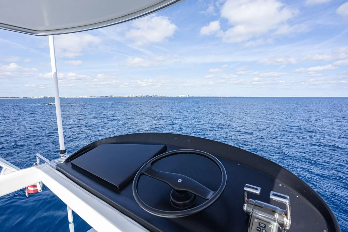 A sleek helm station with a modern steering wheel and navigation equipment overlooks the vast ocean. aboard HT HOOK Yacht for Sale
