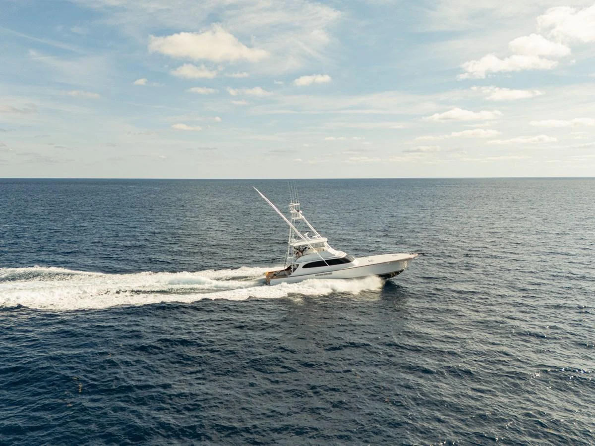 A sleek yacht cruises swiftly across the open sea under a clear sky. aboard HT HOOK Yacht for Sale