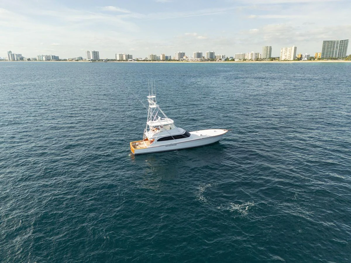A sleek yacht cruises on calm waters with a city skyline in the background. aboard HT HOOK Yacht for Sale