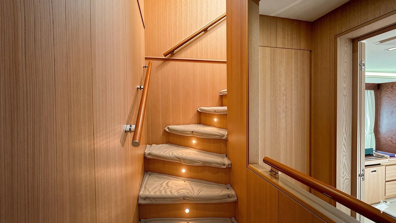 A beautifully crafted wooden staircase with soft lighting leads to the upper deck. aboard SEA PEARL 2 Yacht for Sale