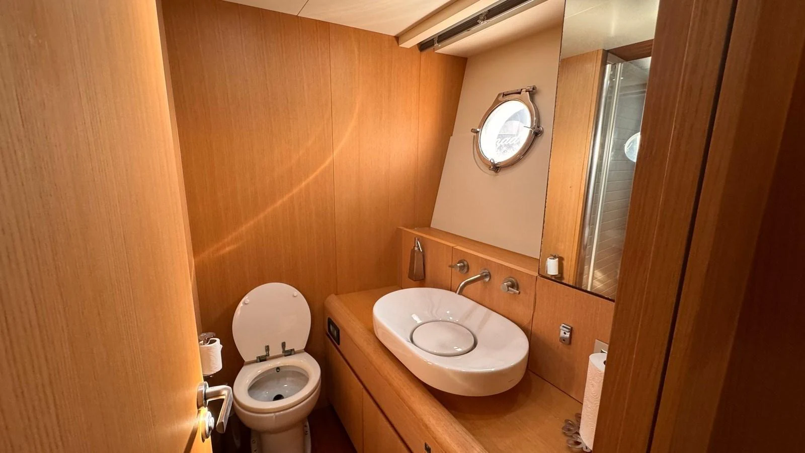 The yacht's head features a sleek, modern design with wooden finishes and a porthole window. aboard SEA PEARL 2 Yacht for Sale