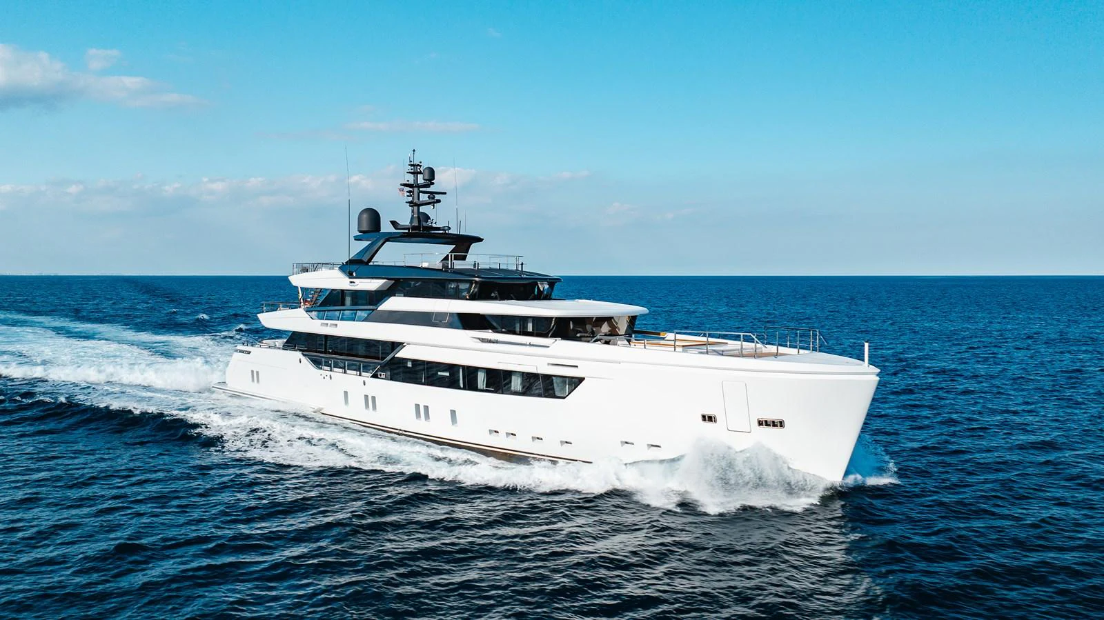 A sleek and modern yacht cruises through the open sea under a clear blue sky. aboard NEVERLAND II Yacht for Sale