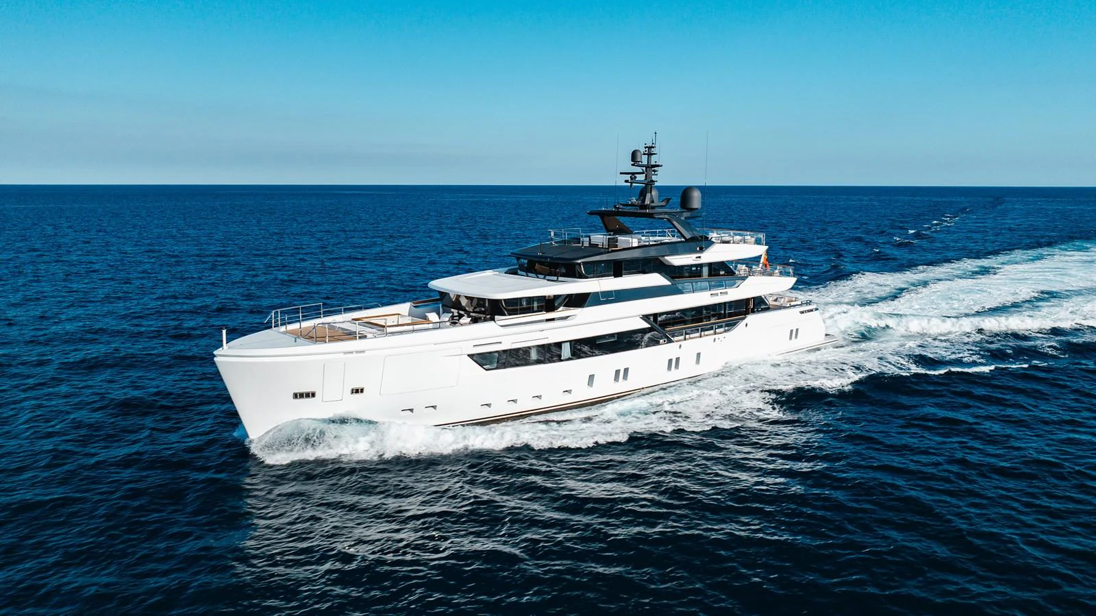 A sleek and modern yacht cruises through the open sea under a clear blue sky. aboard NEVERLAND II Yacht for Sale