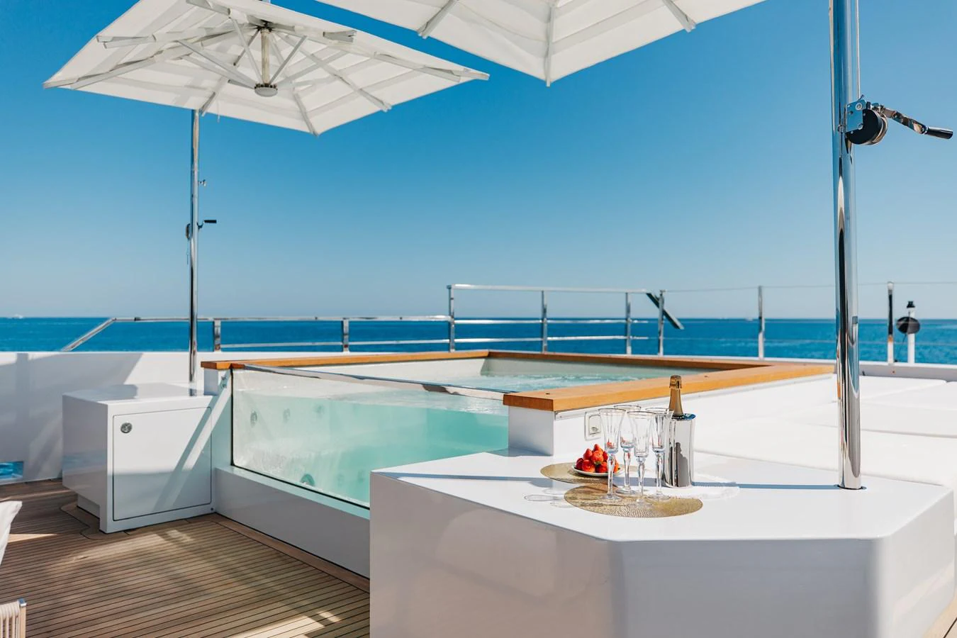 The sundeck features a luxurious jacuzzi with a stunning ocean view, complemented by a shaded seating area and a bar setup. aboard NEVERLAND II Yacht for Sale