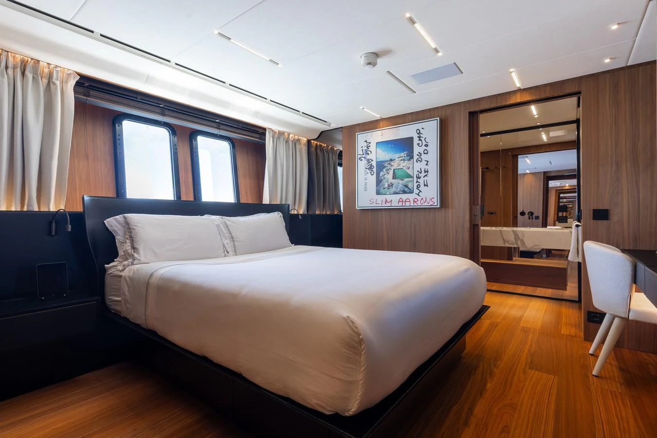 The stateroom features a luxurious bed with elegant wood paneling and modern decor. aboard NEVERLAND II Yacht for Sale