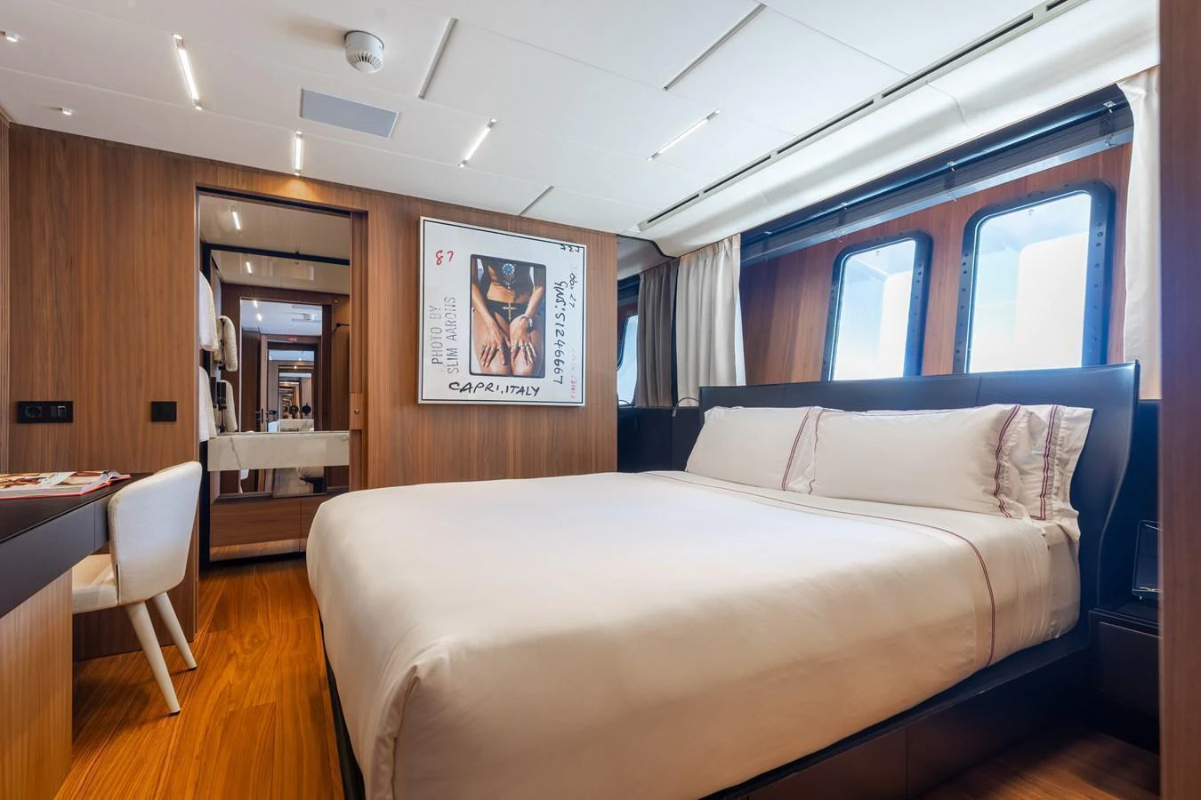 The stateroom features a luxurious bed with elegant wood paneling and large windows for natural light. aboard NEVERLAND II Yacht for Sale