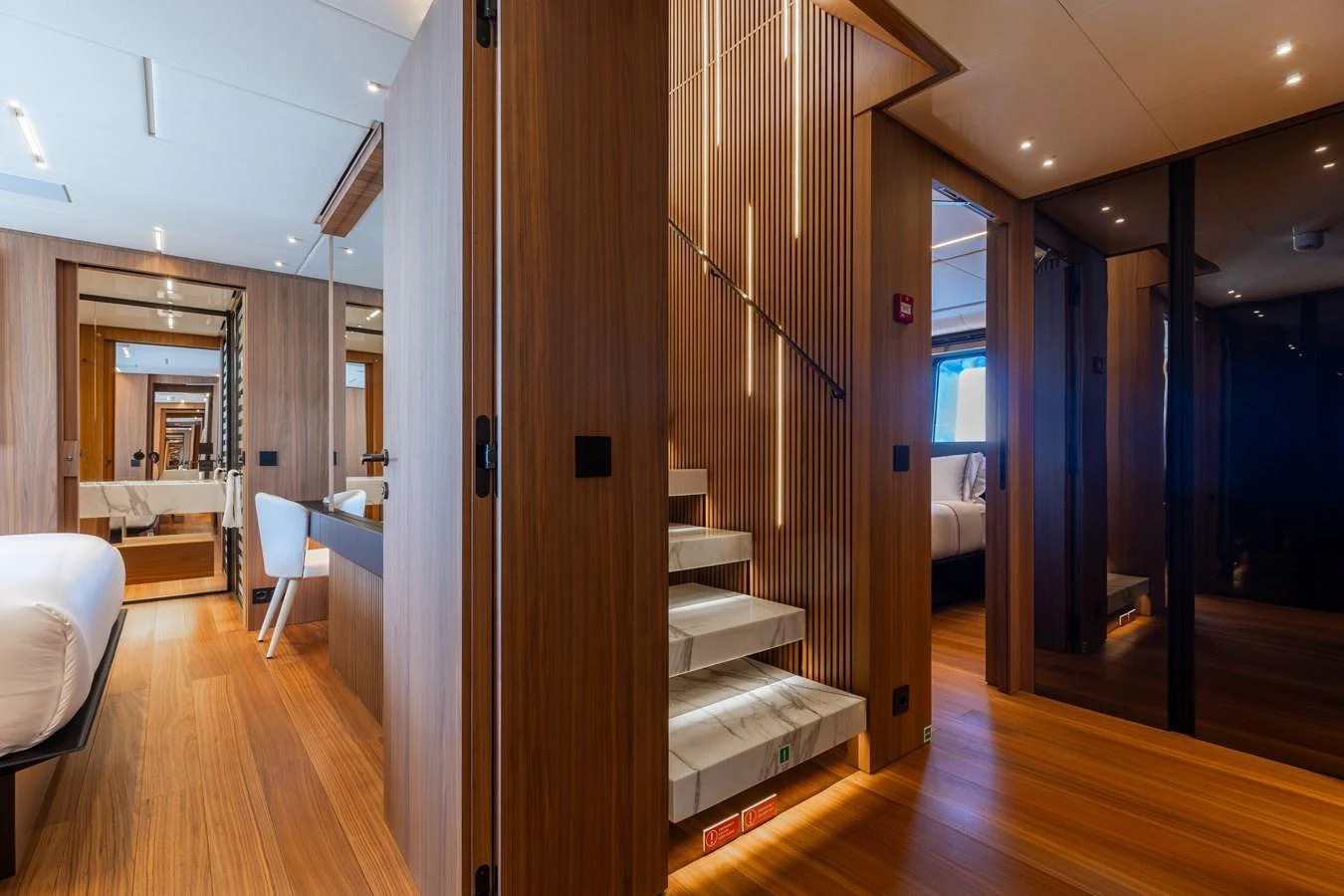 The interior features a modern staircase with sleek wooden paneling and ambient lighting. aboard NEVERLAND II Yacht for Sale