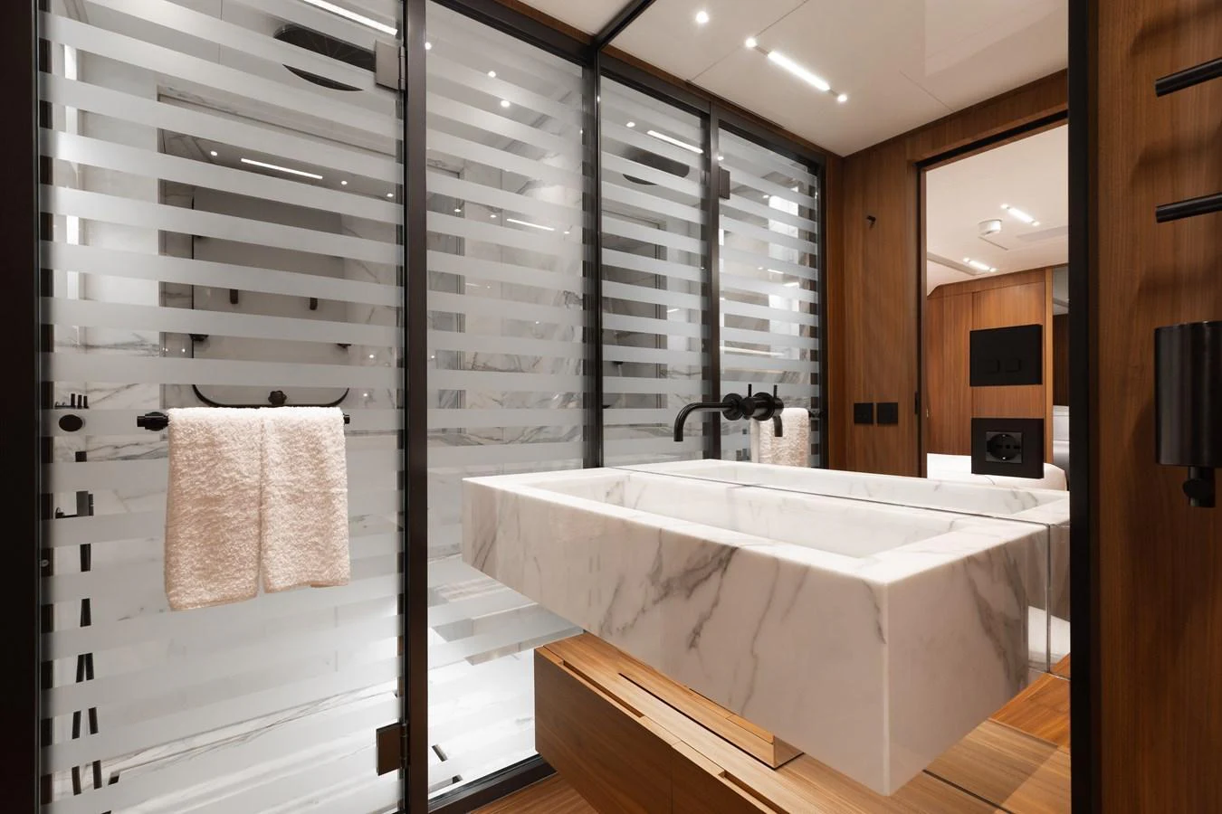 The yacht's bathroom features a sleek, modern design with a marble sink and frosted glass shower enclosure. aboard NEVERLAND II Yacht for Sale