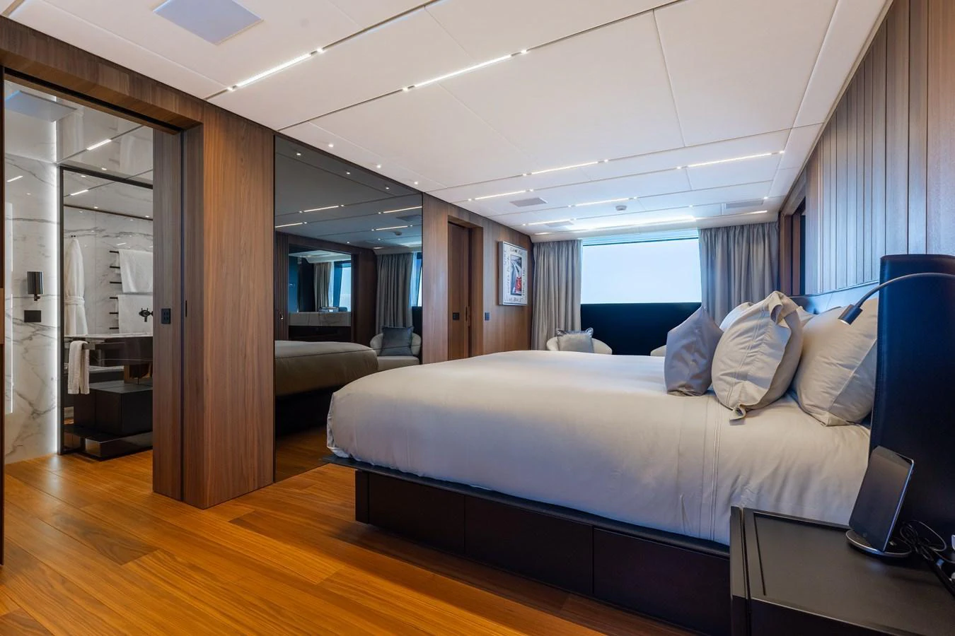 The master stateroom features a spacious bed, elegant wood finishes, and a luxurious en-suite bathroom. aboard NEVERLAND II Yacht for Sale