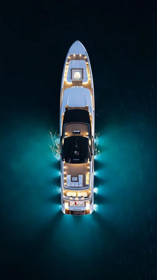 A stunning aerial view of a yacht illuminated at night, showcasing its sleek design and elegant lighting. aboard NEVERLAND II Yacht for Sale