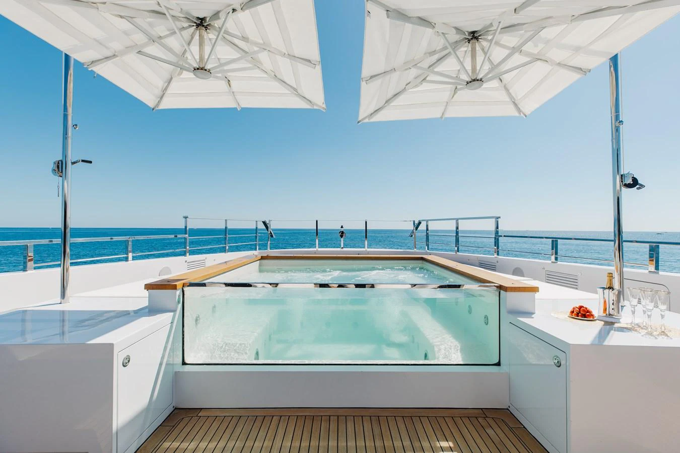 The sundeck features a luxurious jacuzzi with surrounding sun loungers and parasols, offering a perfect relaxation spot with stunning ocean views. aboard NEVERLAND II Yacht for Sale