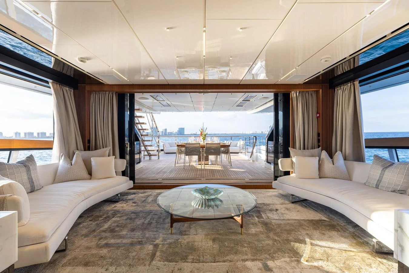 The spacious salon features elegant seating and opens up to a stunning aft deck with a dining area. aboard NEVERLAND II Yacht for Sale