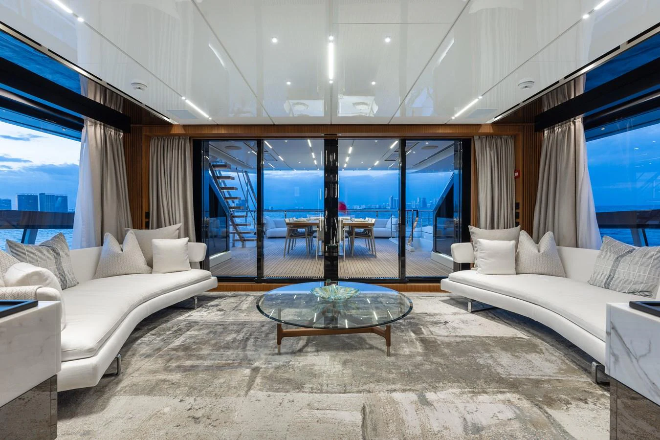 The salon offers a spacious and luxurious seating area with a stunning view through large glass doors leading to the aft deck. aboard NEVERLAND II Yacht for Sale