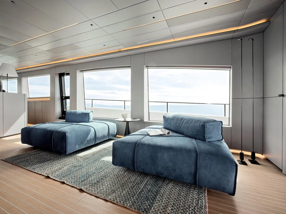 The stateroom features two plush blue lounge chairs with expansive windows offering stunning ocean views. aboard 50 SHADES OF PLAY Yacht for Sale