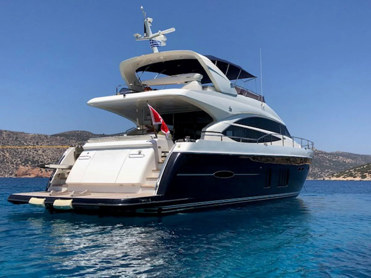 A luxurious yacht anchored in clear blue waters with a stunning backdrop of hills and a clear sky. aboard LAVIMAR II Yacht for Sale