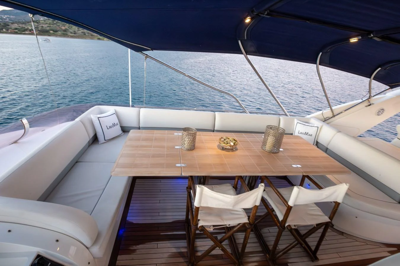 The aft deck features a comfortable seating area with a wooden dining table, perfect for alfresco dining. aboard LAVIMAR II Yacht for Sale