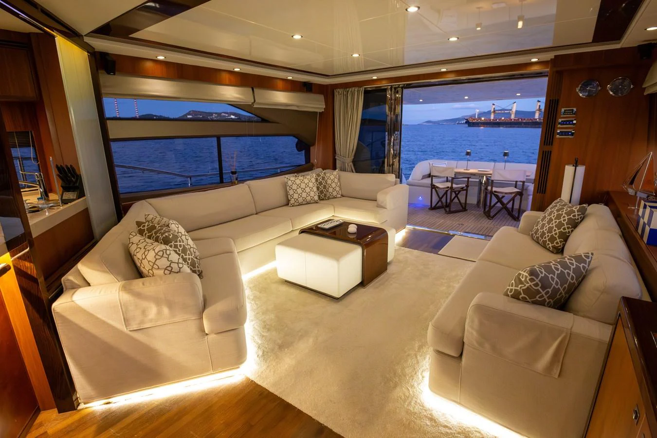 The salon features plush seating with a view of the ocean through large windows and an open aft deck. aboard LAVIMAR II Yacht for Sale