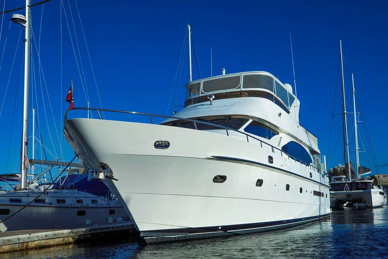 A sleek and modern yacht docked at a marina under a clear blue sky. aboard MELODIOUS LL Yacht for Sale