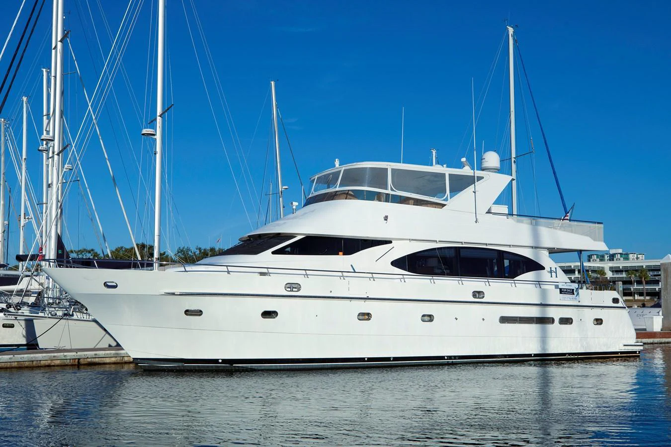 A sleek and elegant yacht is docked at the marina, showcasing its pristine white exterior against a clear blue sky. aboard MELODIOUS LL Yacht for Sale