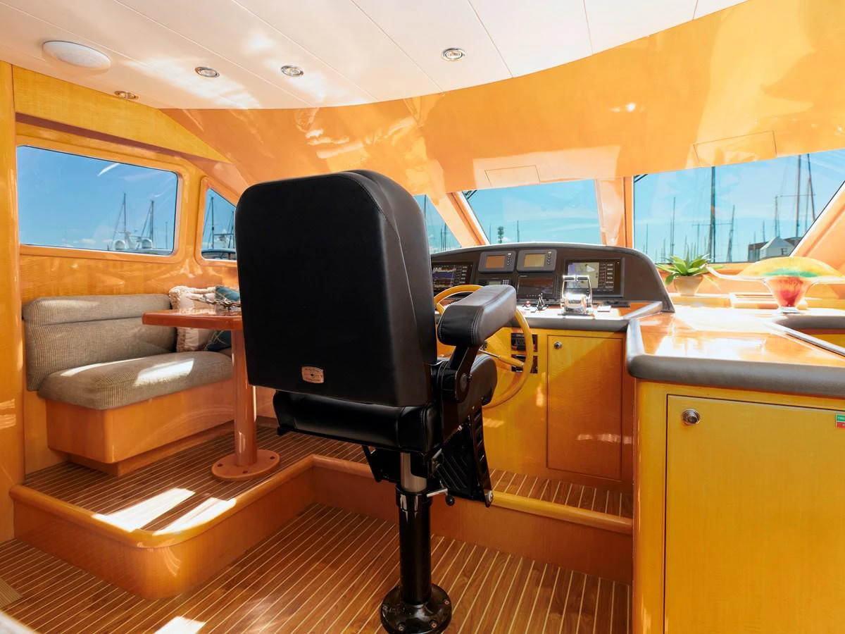 The helm station features a sleek design with a comfortable captain's chair and panoramic windows offering a clear view of the marina. aboard MELODIOUS LL Yacht for Sale
