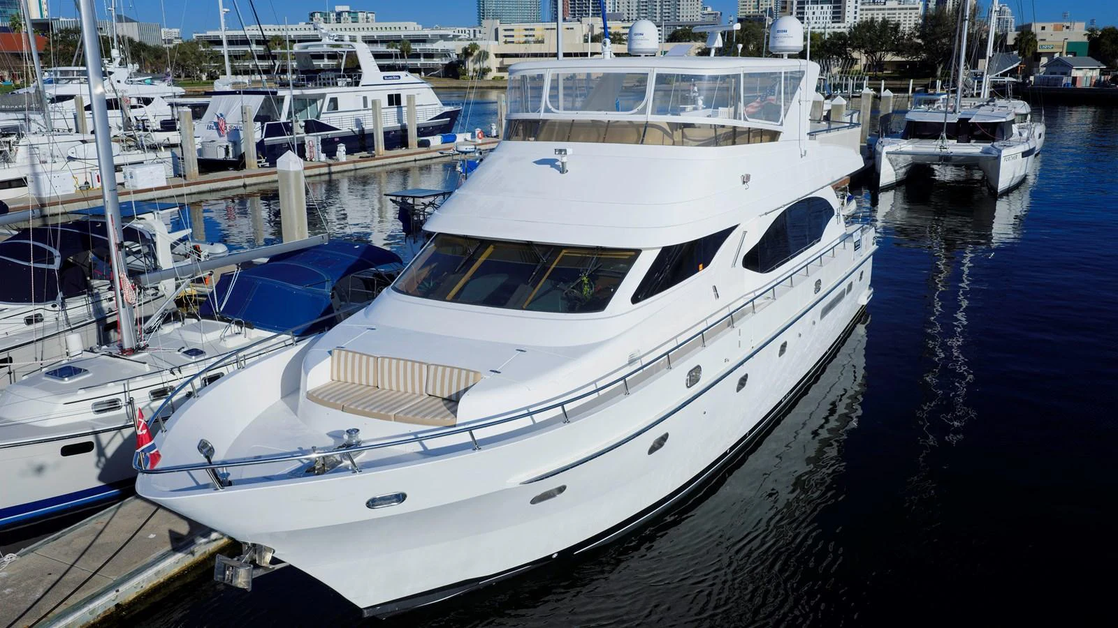 A sleek and modern yacht docked at a marina, showcasing its elegant design and spacious deck. aboard MELODIOUS LL Yacht for Sale