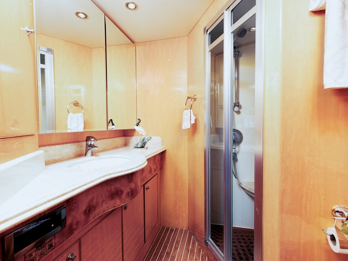 The yacht's bathroom features a sleek design with a glass-enclosed shower and elegant wooden cabinetry. aboard MELODIOUS LL Yacht for Sale