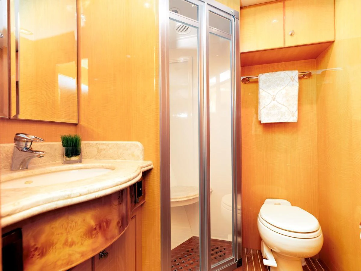 The yacht's bathroom features a sleek design with a glass-enclosed shower and elegant wooden finishes. aboard MELODIOUS LL Yacht for Sale