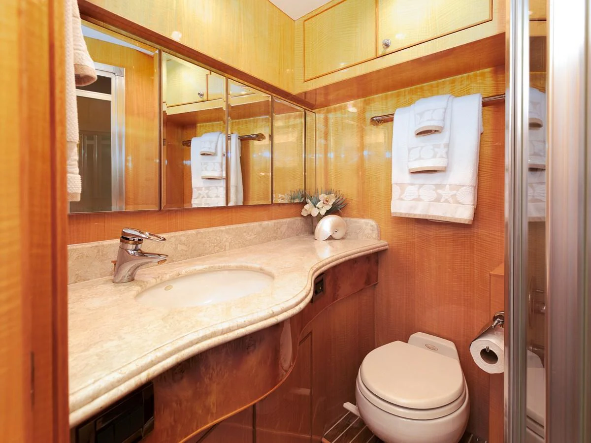 The yacht's bathroom features elegant wood finishes and a sleek marble countertop. aboard MELODIOUS LL Yacht for Sale