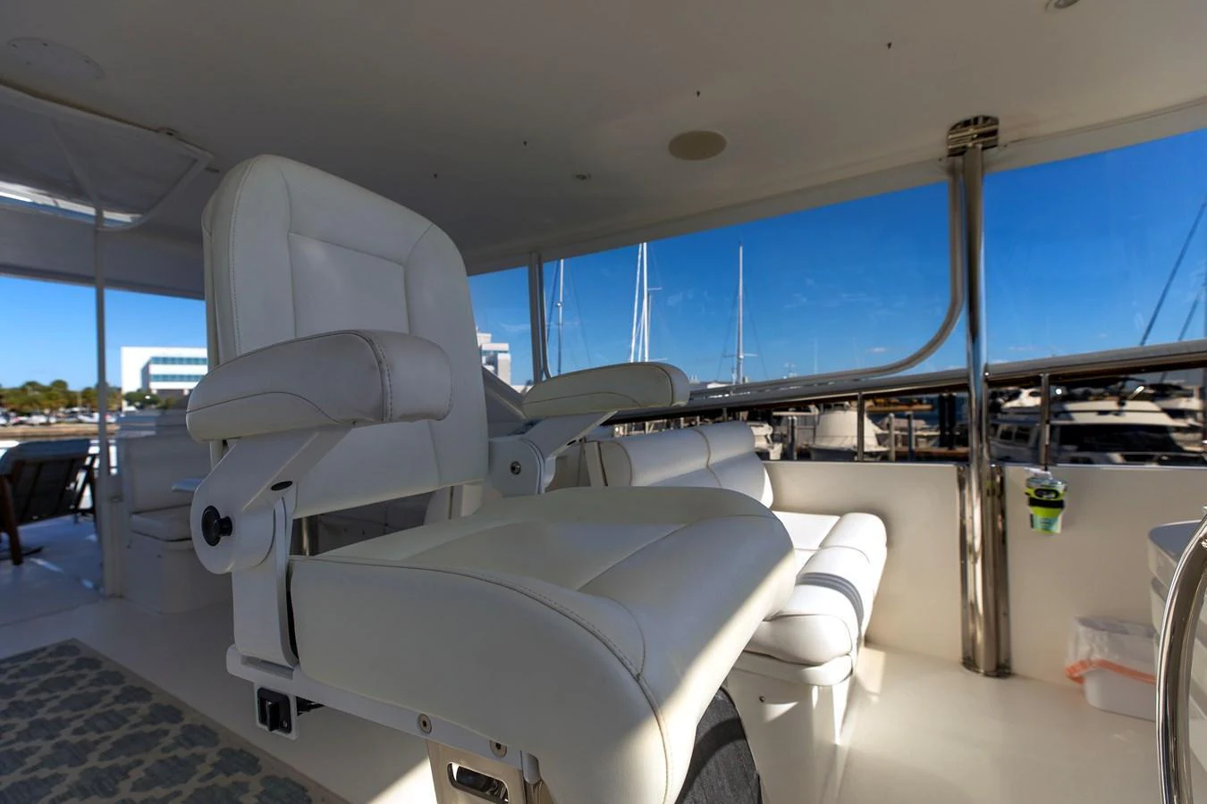 The yacht's helm features a comfortable white captain's chair with a view of the marina. aboard MELODIOUS LL Yacht for Sale