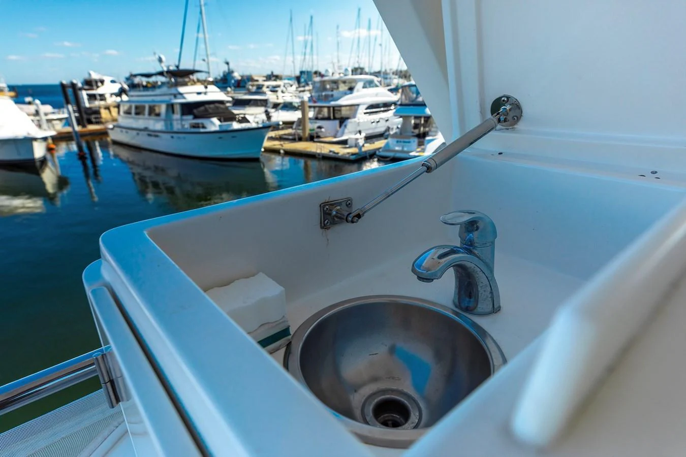 A close-up view of a sleek sink on the yacht with a marina in the background. aboard MELODIOUS LL Yacht for Sale