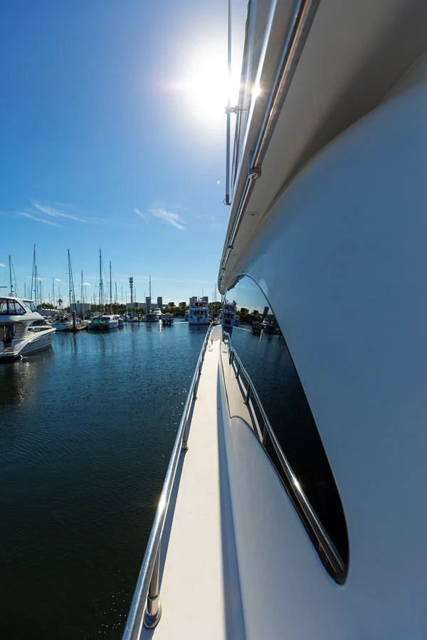 The yacht is docked in a serene marina under a clear blue sky. aboard MELODIOUS LL Yacht for Sale