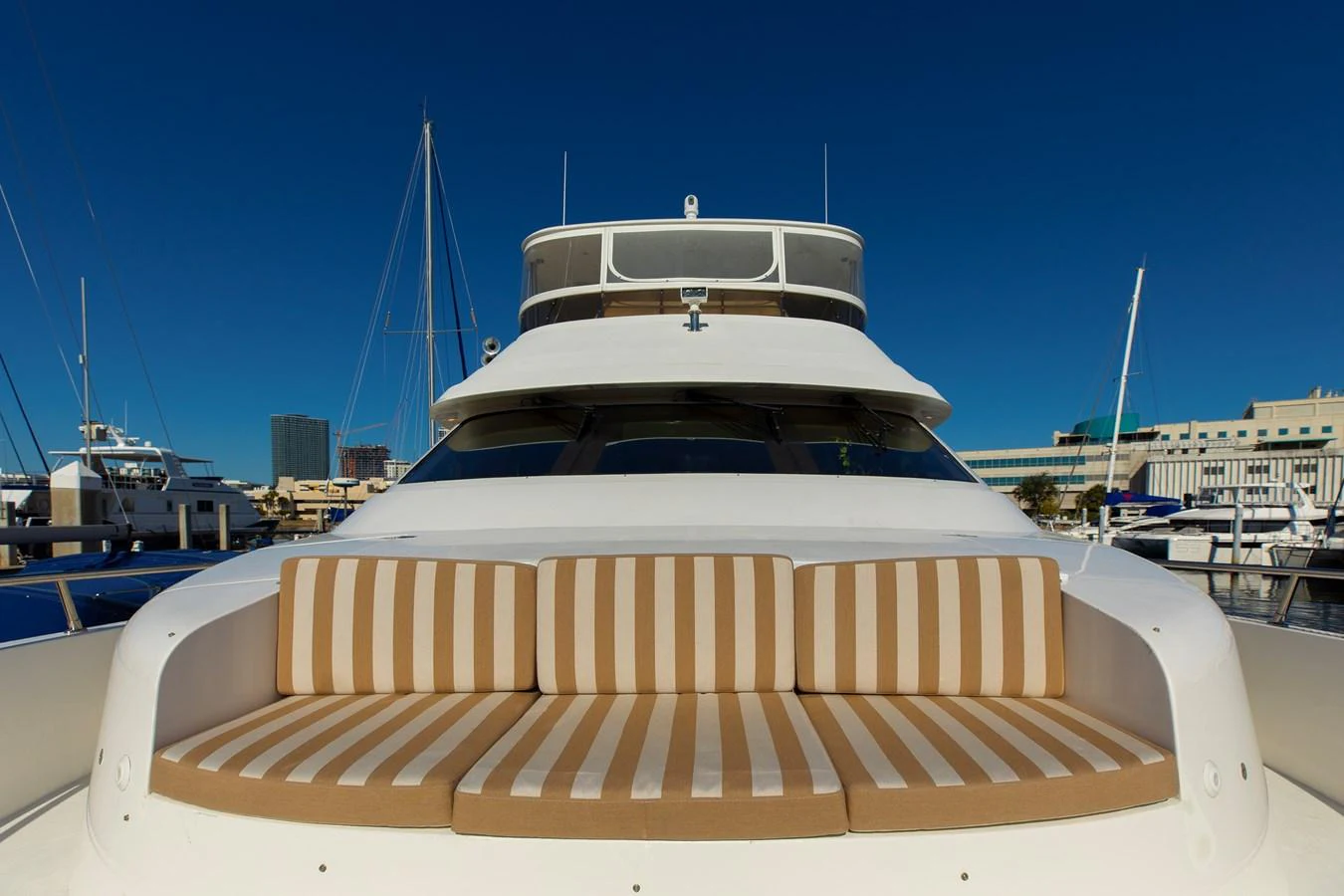 A luxurious yacht bow area with striped seating under a clear blue sky. aboard MELODIOUS LL Yacht for Sale