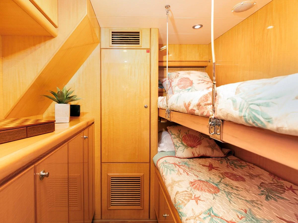 The cozy guest cabin features wooden finishes and comfortable bunk beds with floral bedding. aboard MELODIOUS LL Yacht for Sale