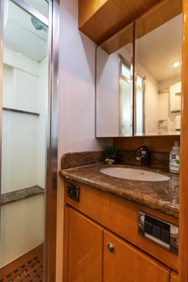 The yacht's bathroom features a sleek design with a marble countertop and a modern shower. aboard MELODIOUS LL Yacht for Sale