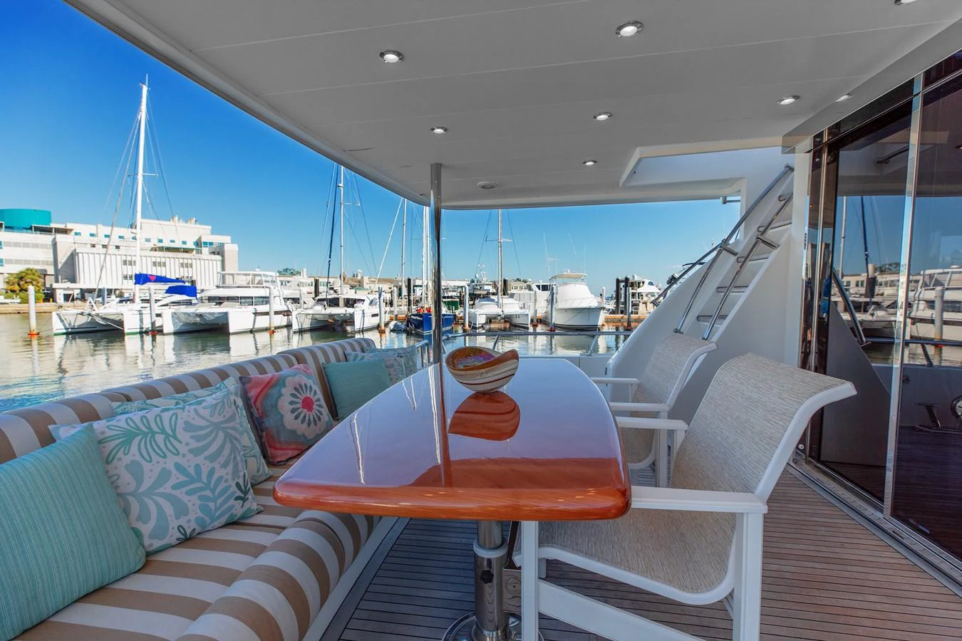 The aft deck offers a comfortable seating area with a polished wooden table, perfect for alfresco dining. aboard MELODIOUS LL Yacht for Sale