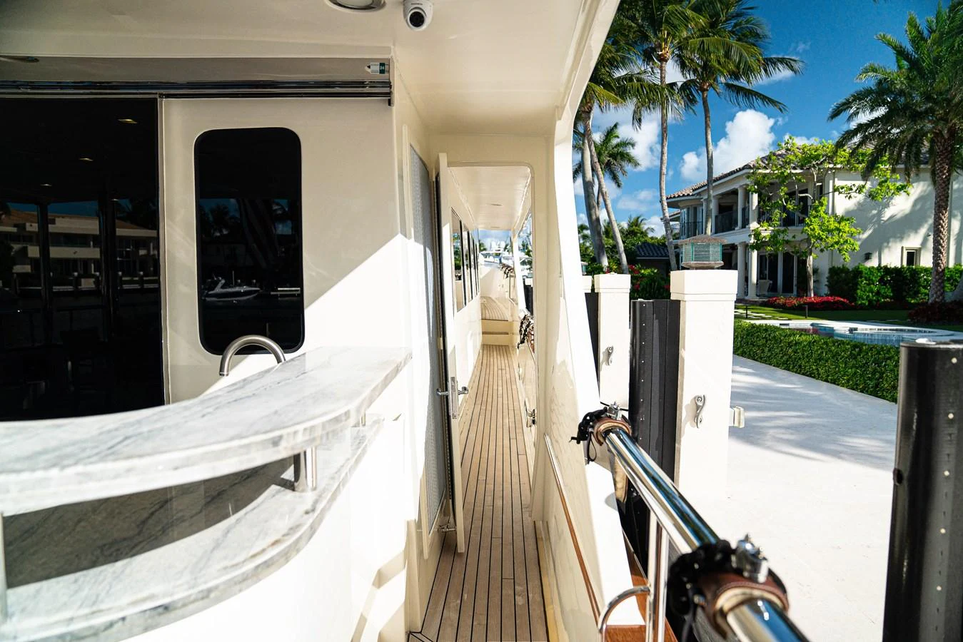 a deck with a railing and palm trees and a building with palm trees aboard TOP TIMES Yacht for Sale