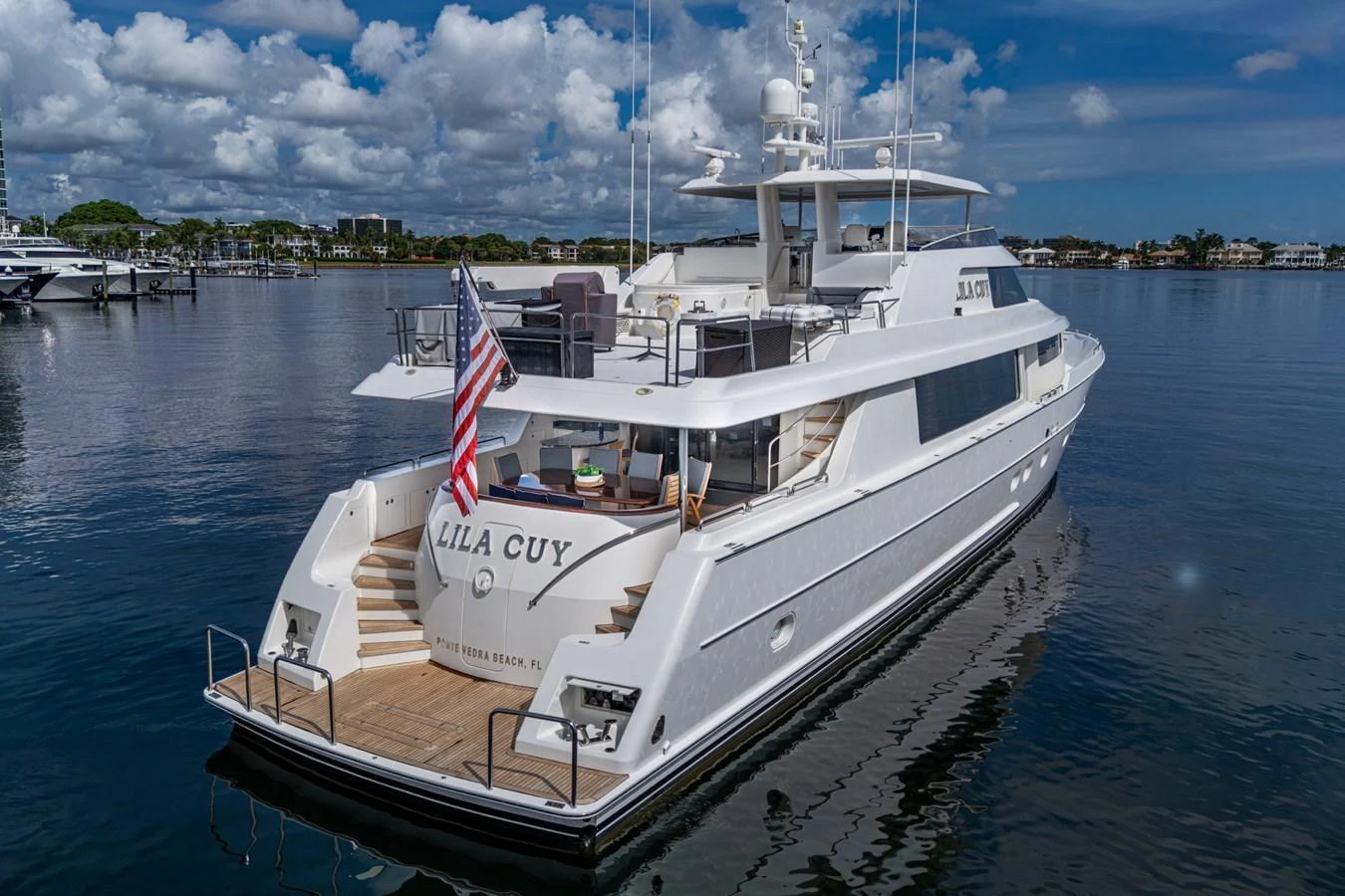 A luxurious yacht is docked in a serene marina, showcasing its elegant aft deck and sleek design. aboard LILA CUY Yacht for Sale
