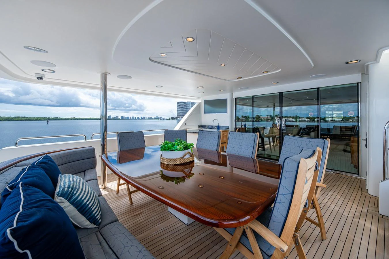 The aft deck features a spacious dining area with a polished wooden table and comfortable seating, perfect for al fresco meals with a view. aboard LILA CUY Yacht for Sale
