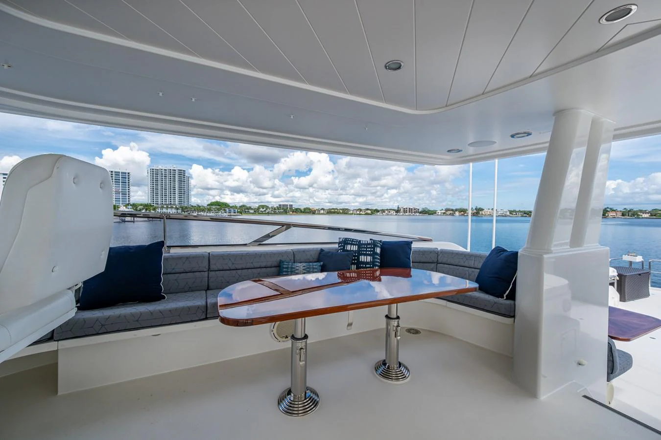 The aft deck features a comfortable seating area with a polished wooden table, offering stunning views of the water. aboard LILA CUY Yacht for Sale