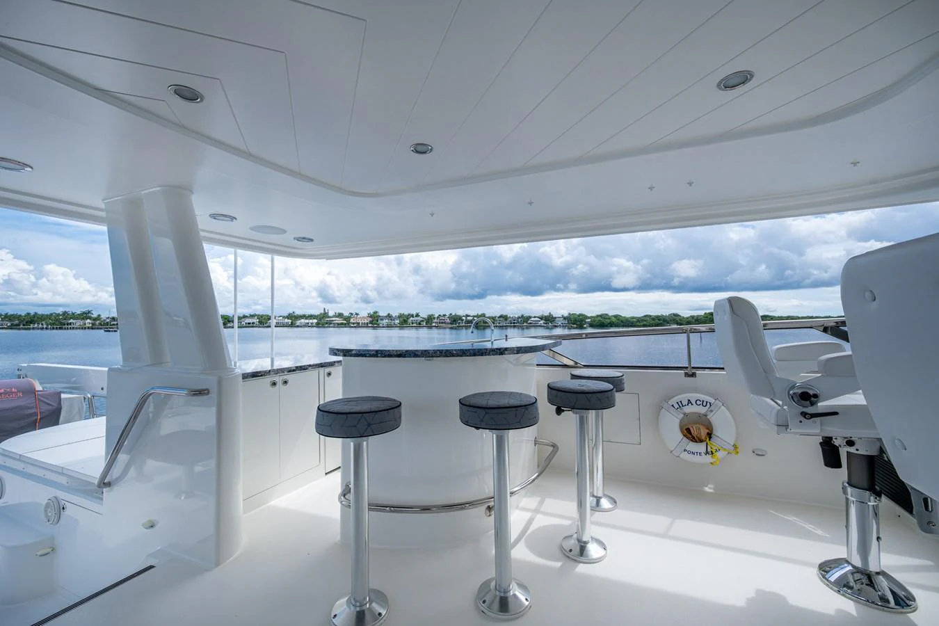 The flybridge offers a spacious and inviting area with bar stools and a panoramic view of the water. aboard LILA CUY Yacht for Sale