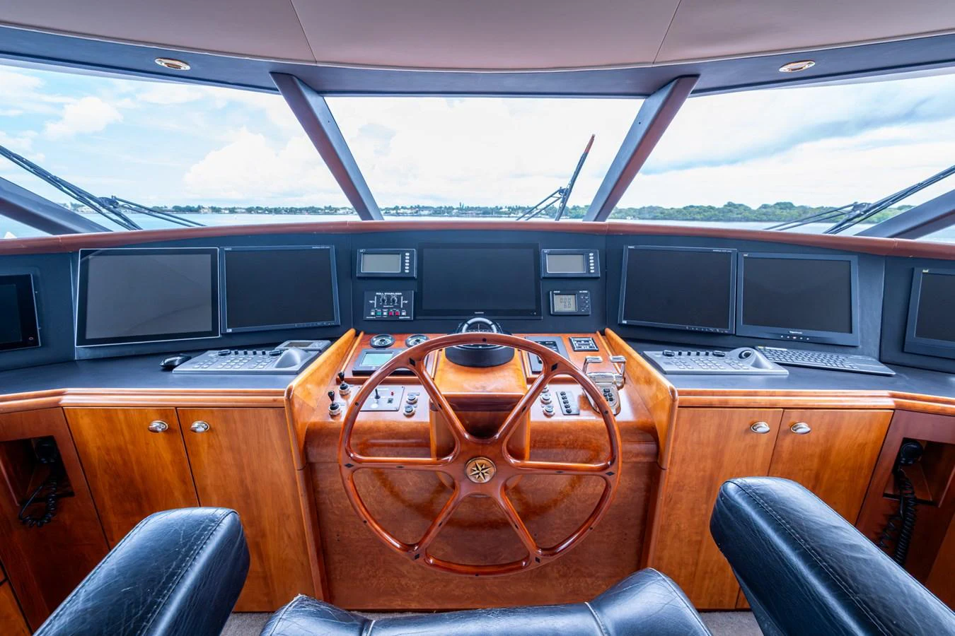 The helm features a sophisticated array of navigation equipment and a classic wooden steering wheel. aboard LILA CUY Yacht for Sale