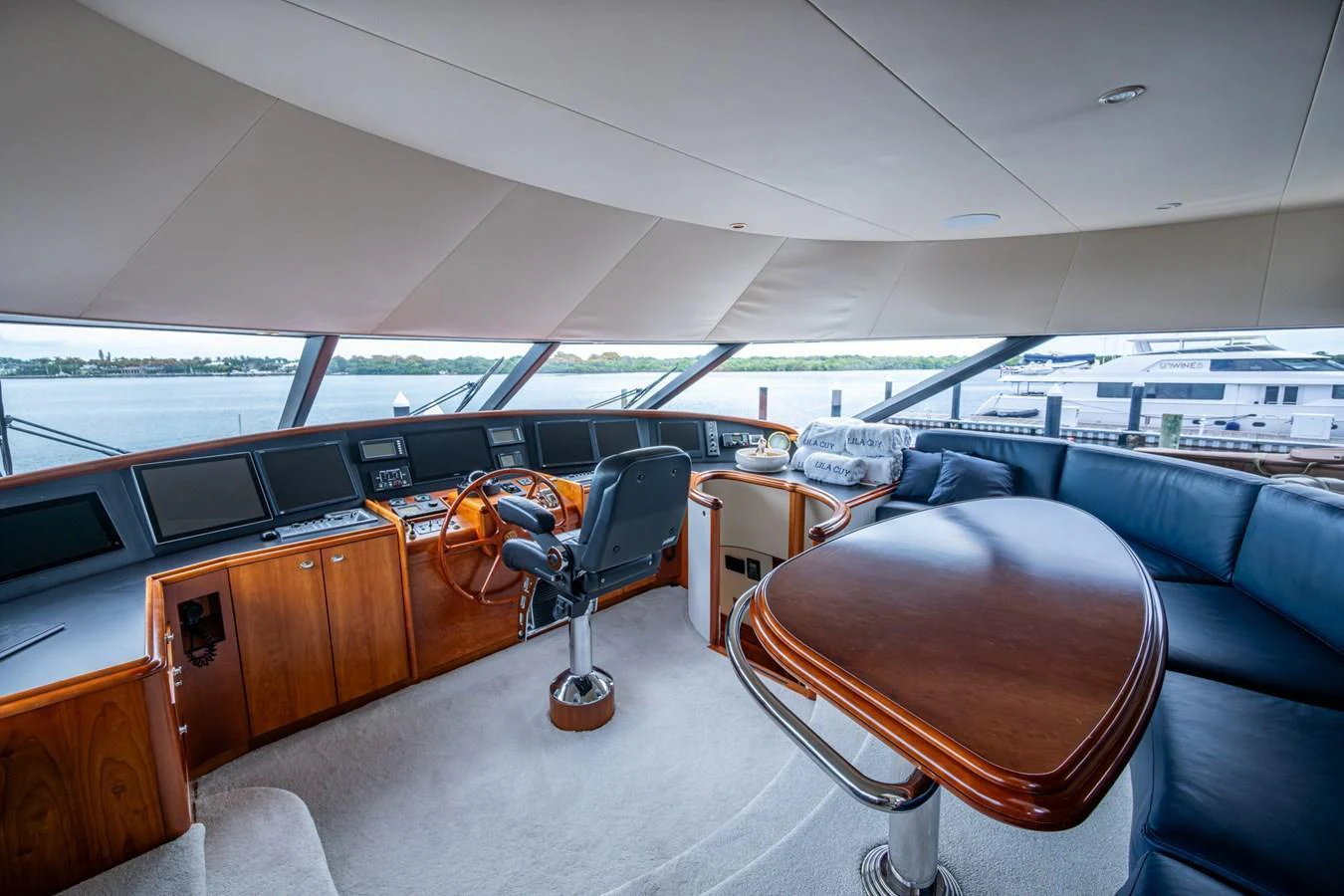 The helm station features a comfortable captain's chair, a sleek wooden console, and panoramic windows offering stunning views. aboard LILA CUY Yacht for Sale