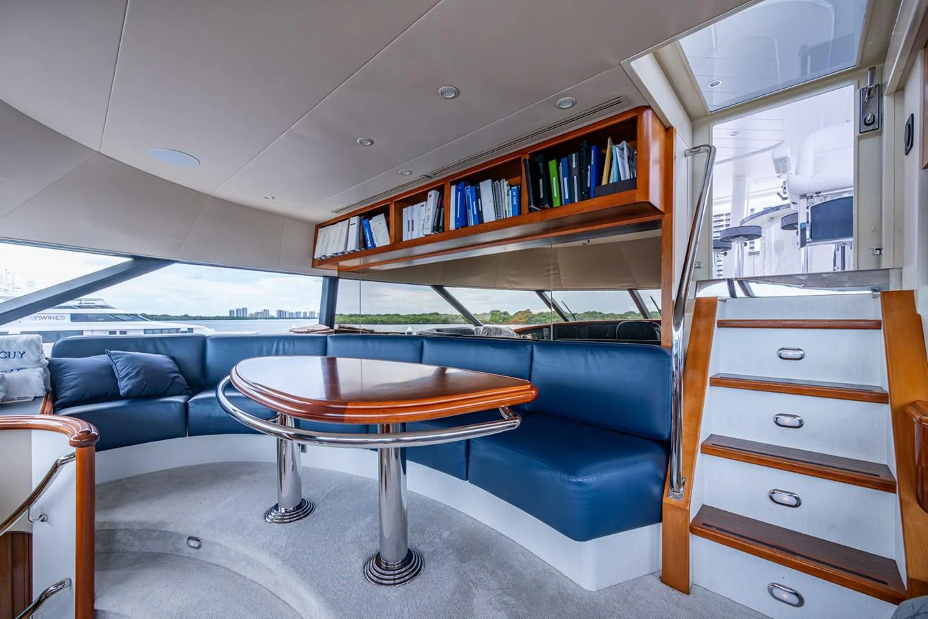The yacht's salon features a comfortable seating area with a polished wooden table and a staircase leading to the upper deck. aboard LILA CUY Yacht for Sale