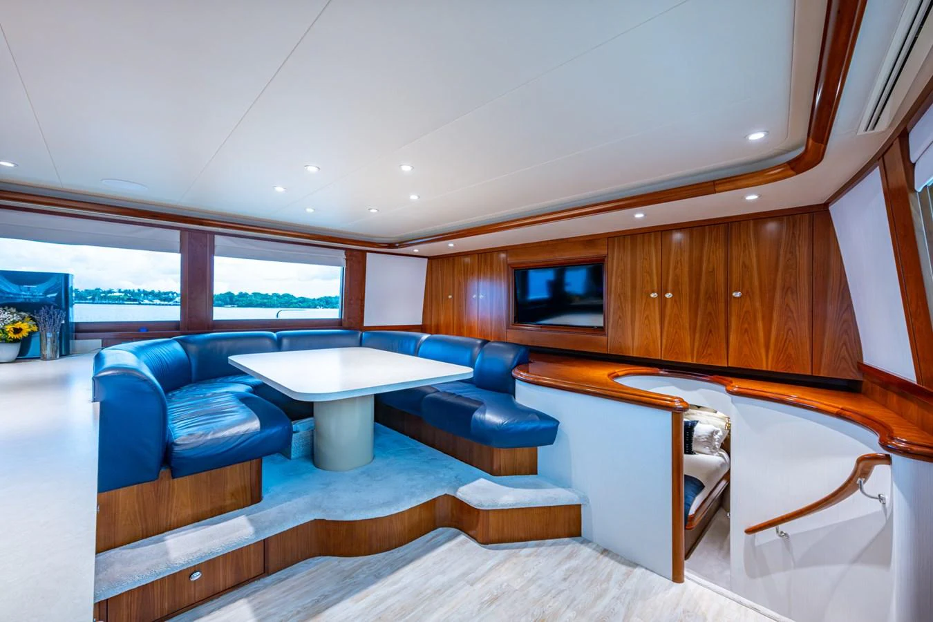 The yacht's saloon features a spacious seating area with plush blue leather upholstery and a large dining table, perfect for social gatherings. aboard LILA CUY Yacht for Sale