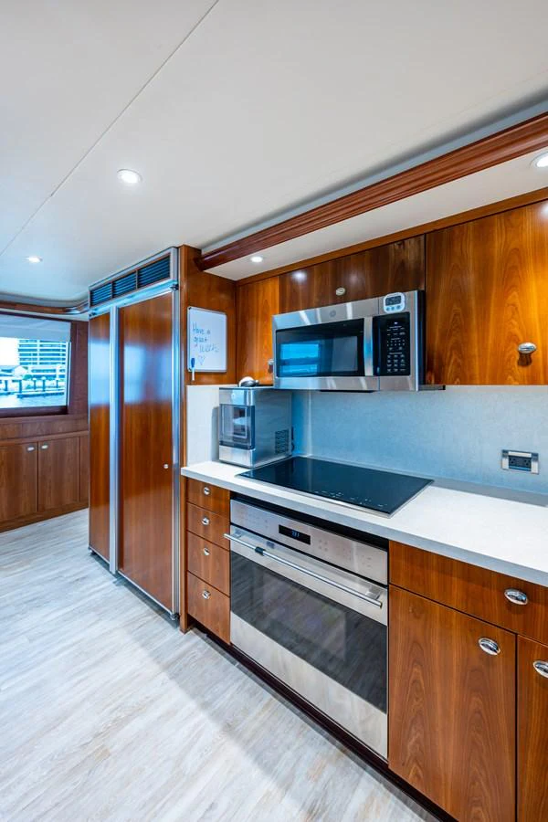 The galley features modern appliances and sleek wooden cabinetry, creating a warm and functional space. aboard LILA CUY Yacht for Sale