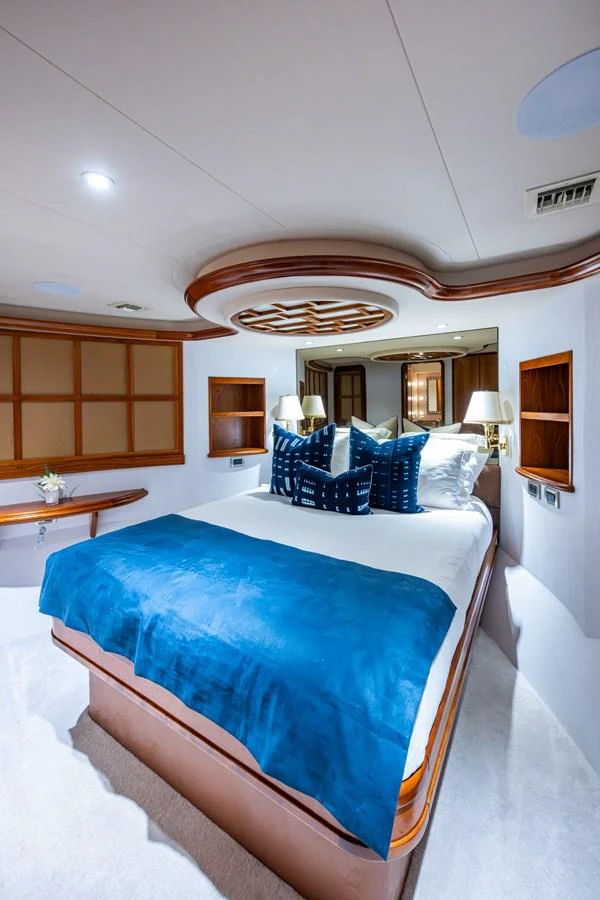 The stateroom features a luxurious bed with plush blue accents and elegant wooden details. aboard LILA CUY Yacht for Sale
