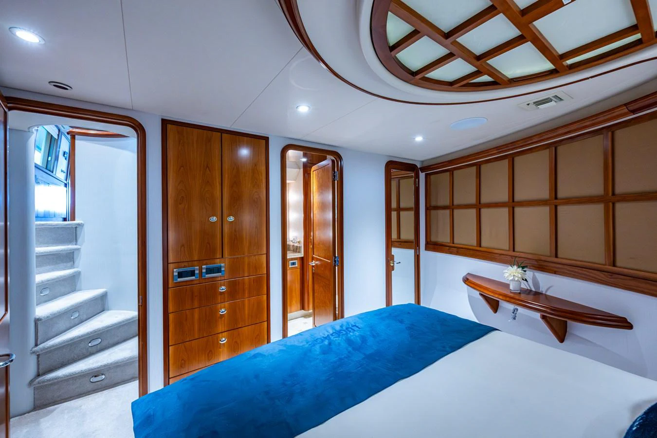 The stateroom features elegant wood paneling and a plush blue bedspread, creating a serene and luxurious atmosphere. aboard LILA CUY Yacht for Sale