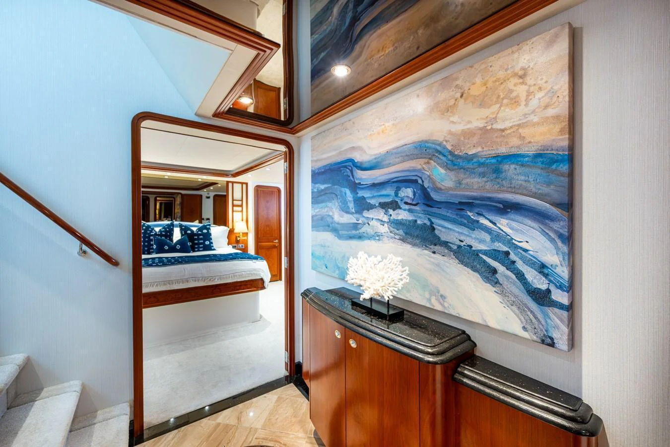 A luxurious hallway with a view into a beautifully appointed stateroom, featuring elegant artwork and refined decor. aboard LILA CUY Yacht for Sale