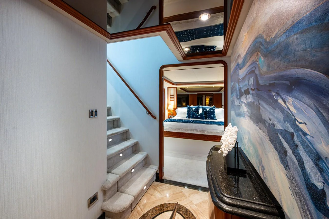 A luxurious interior hallway with a staircase leading to a cozy bedroom adorned with elegant decor. aboard LILA CUY Yacht for Sale