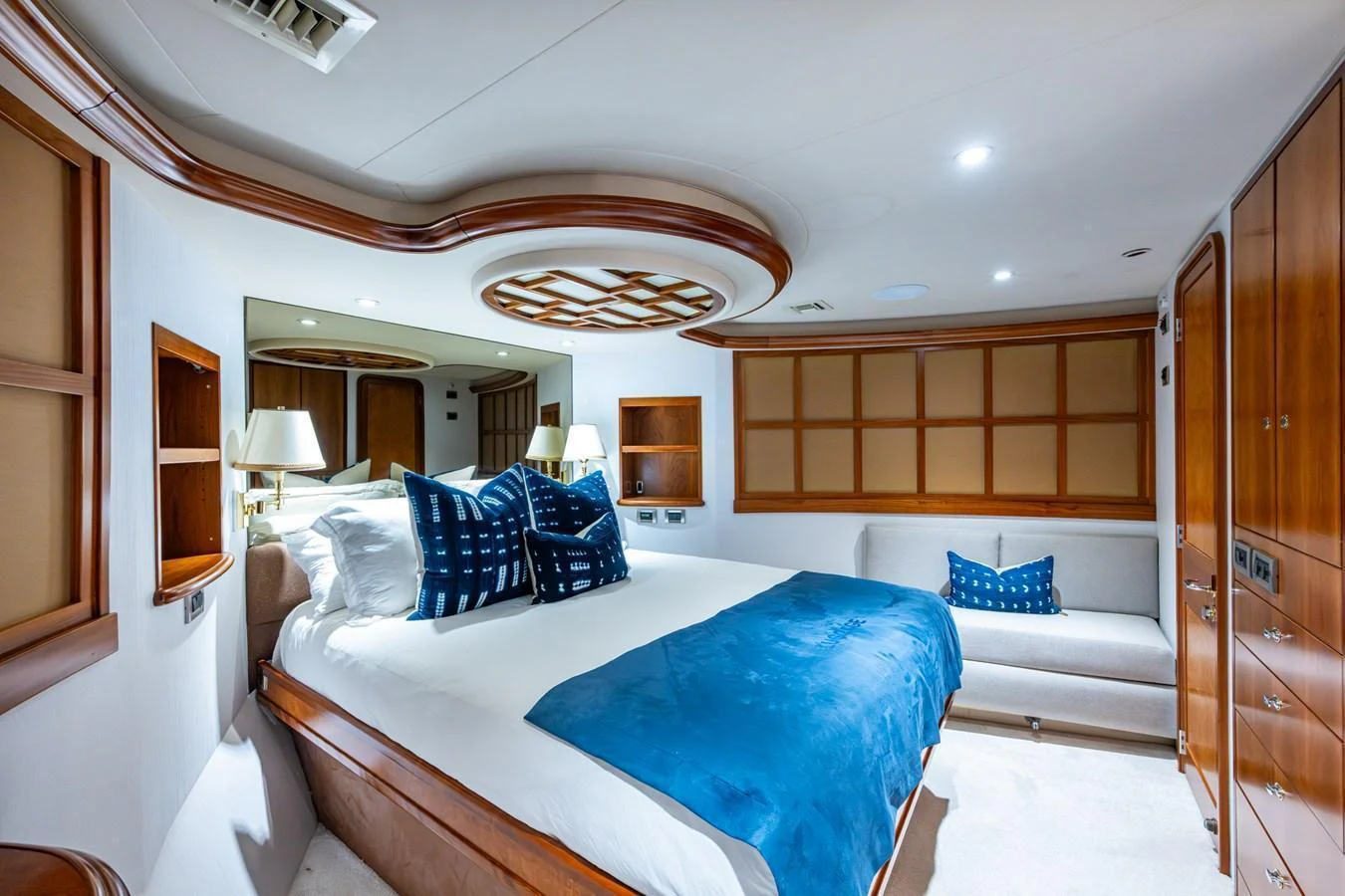 The master stateroom features a luxurious bed with plush blue accents and elegant wooden finishes. aboard LILA CUY Yacht for Sale